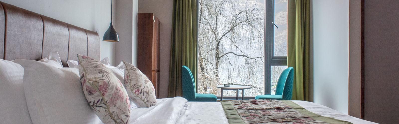 view of the room with a large bed and a balcony view in the background at Mystique Valley Resort  