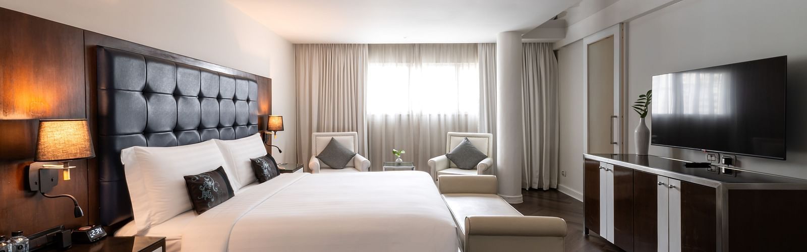 An overview of a double bed with lamps next to the bed inside one of the rooms - Night Hotel Bangkok