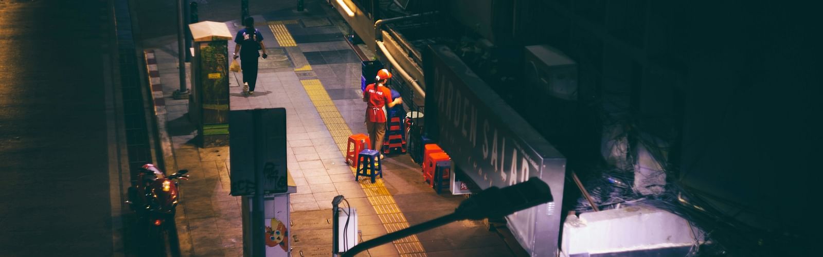 A street photography of a woman working alone in a shop in Bangkok in the night.