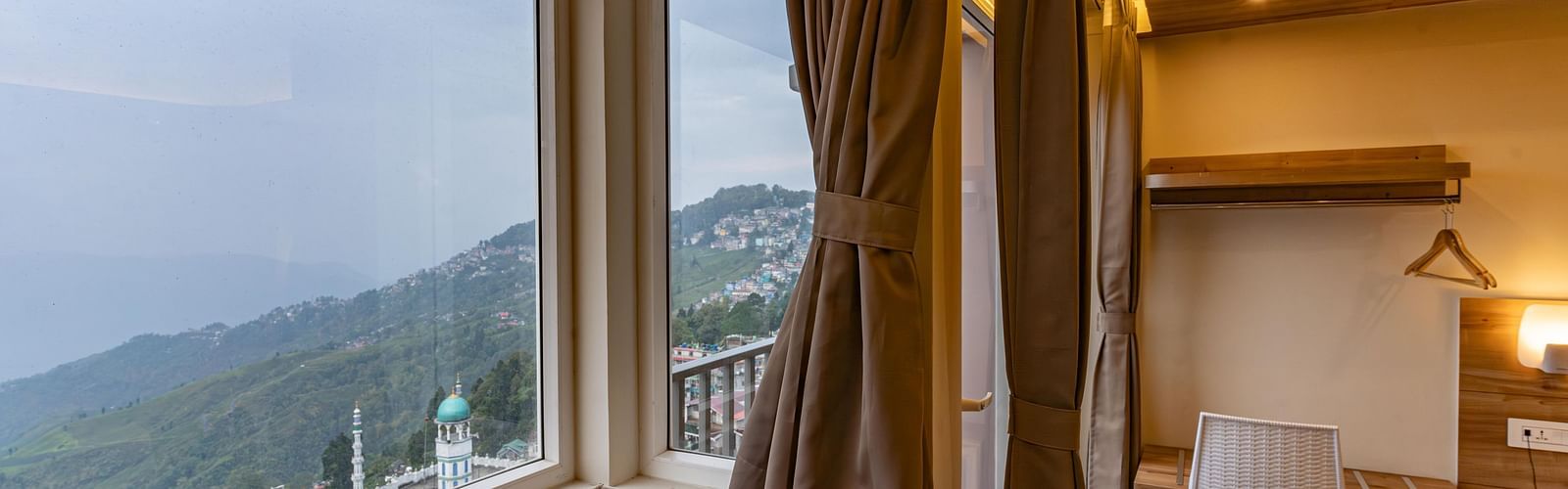 image of the premium room with a huge window exposing serene mountain views at The Soma Hotel by Avianna Group, Darjeeling