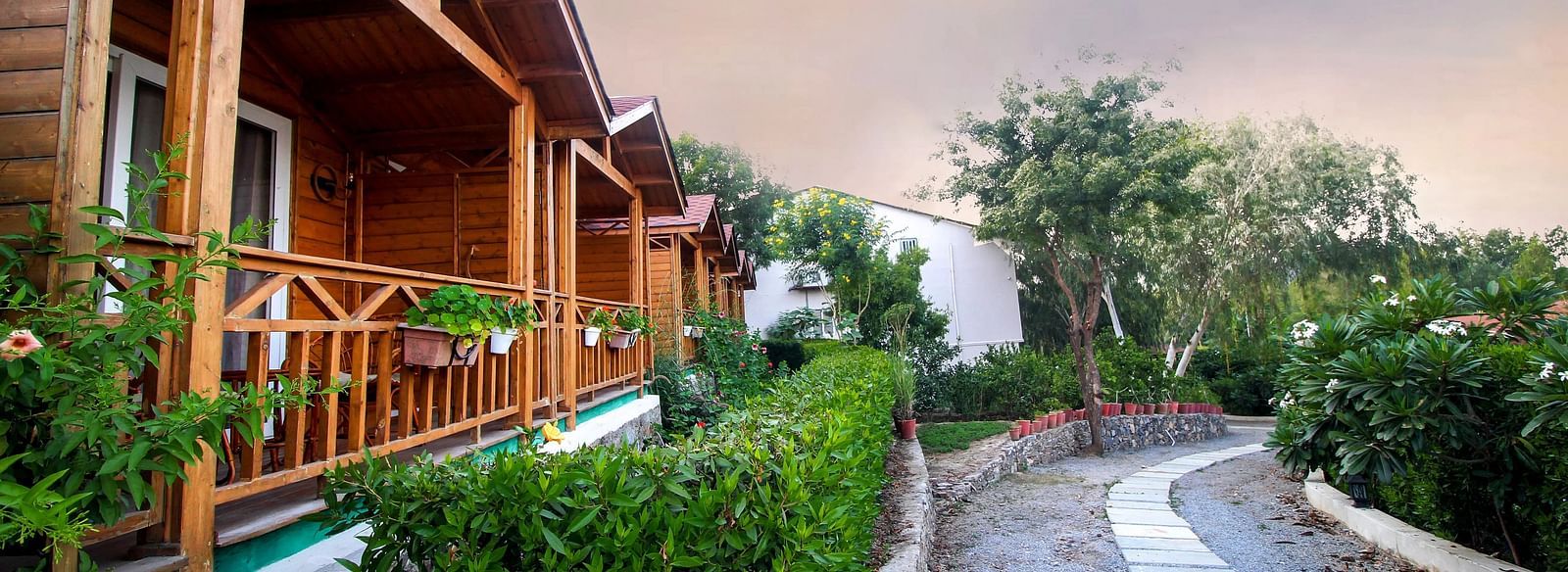 Wooden cabins with green trim along a paved path.