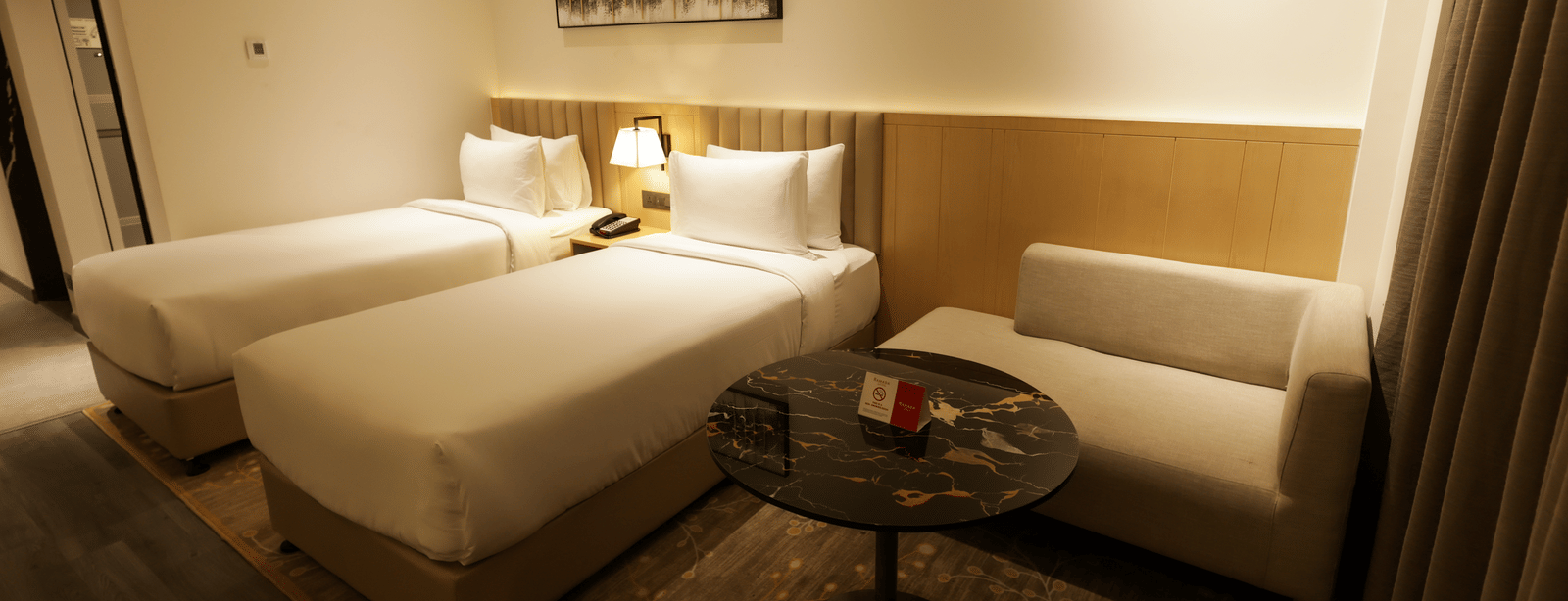 Spacious bedroom with warm lighting and seating area at Ramada by Wyndham Sonipat Murthal