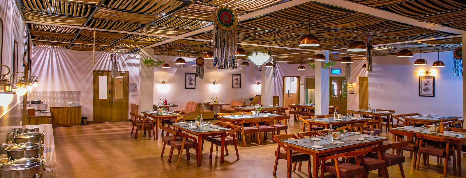 A spacious dining hall at Vedikant Resorts The Mallard Corbett shows multiple tables and chairs under a unique ceiling design.