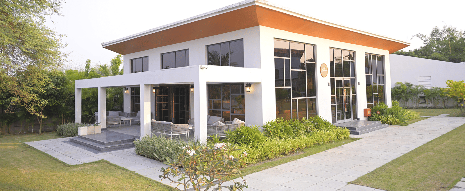 Exterior view of the Sundowner building surrounded by greenery and open lawns at Hotel Sonar Bangla Mayapur.