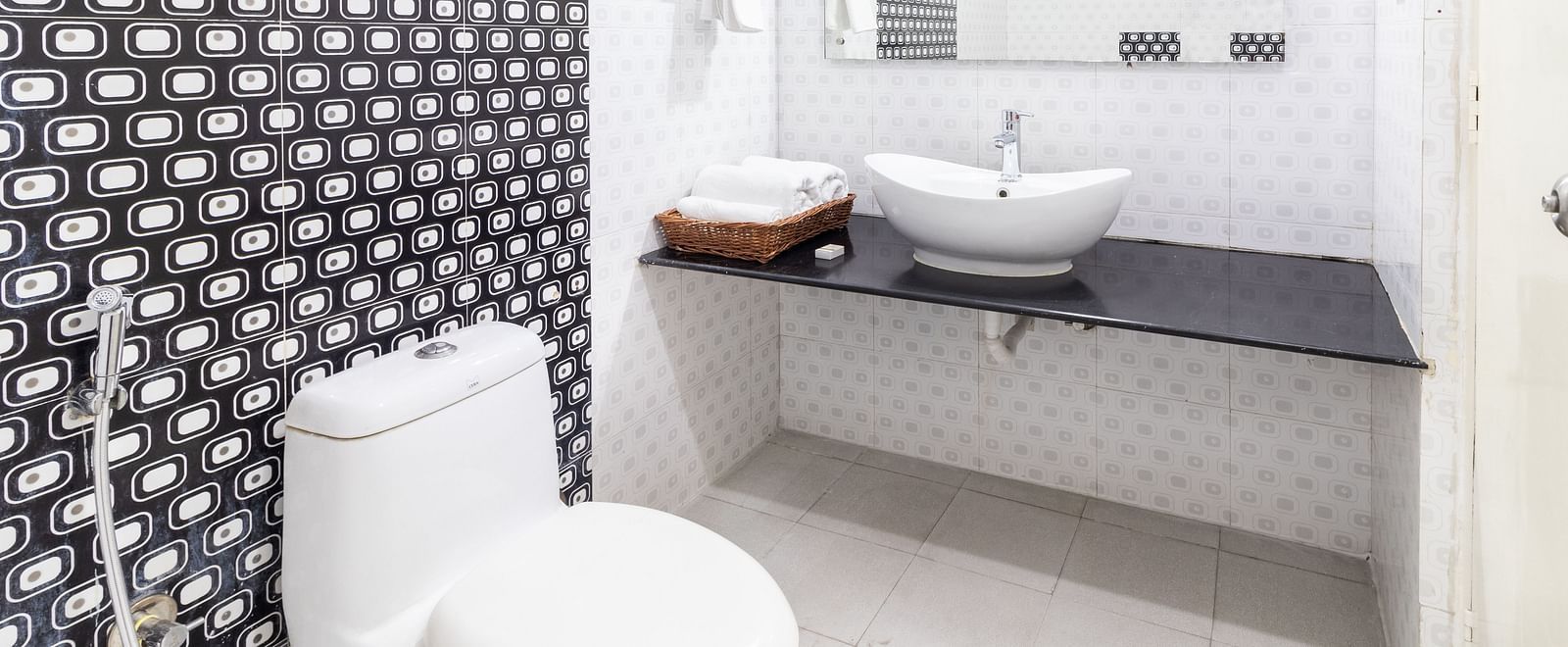 A bathroom featuring a toilet, a sink, and toiletries placed on the counter-top at Sanctum Suites Domlur, Bangalore.