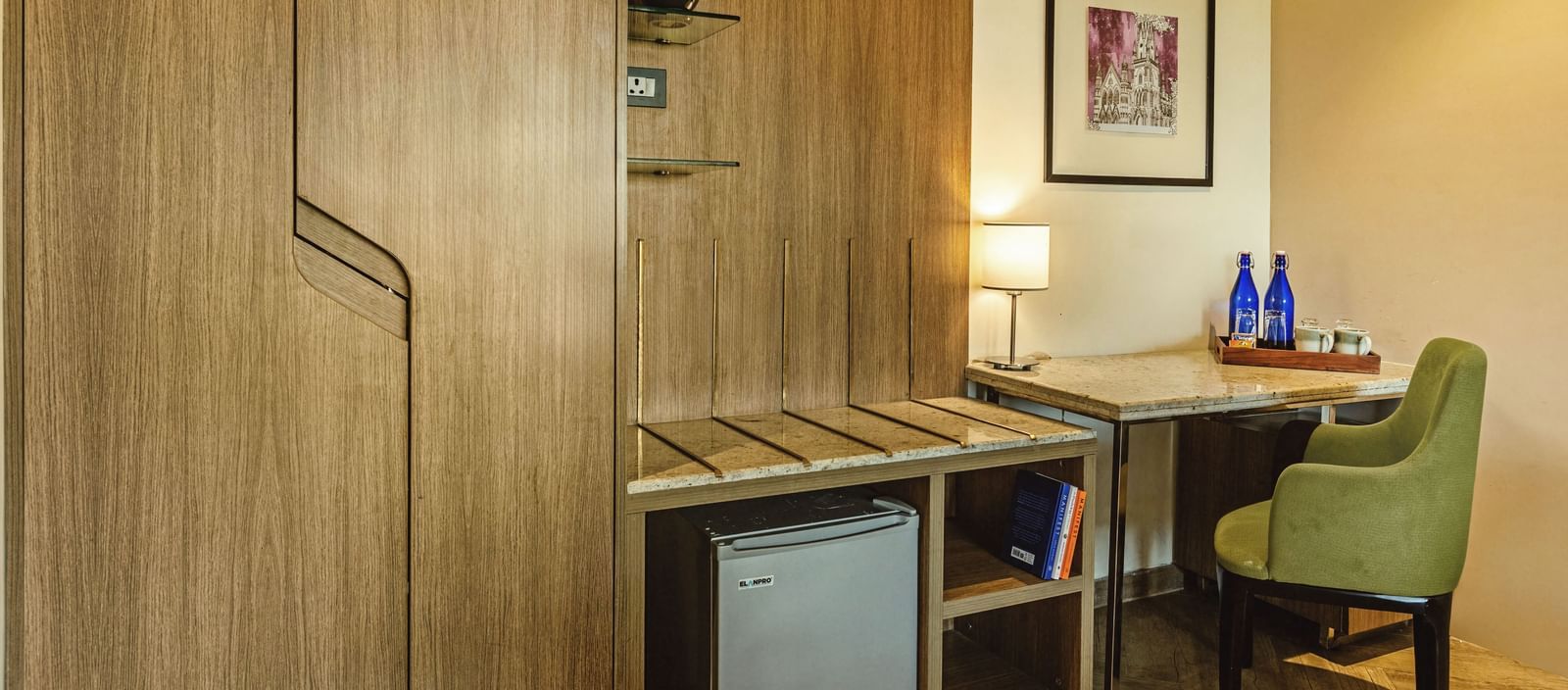 A room at Mango Hill Central, Chennai, with wooden cabinets, a desk, and a small refrigerator.