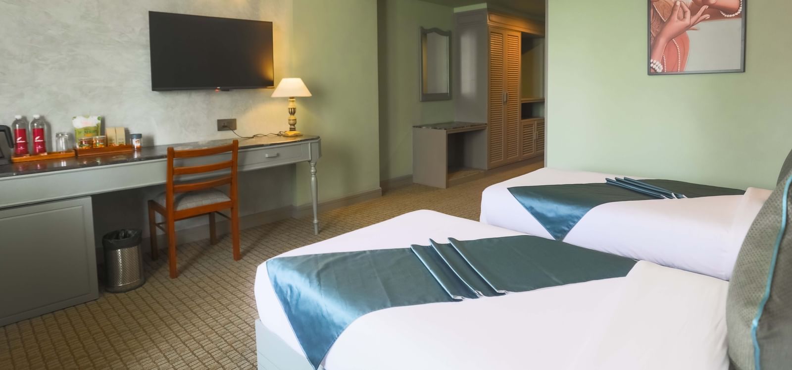  A twin bedroom at Shilton International, Kochi, with a television, a work desk, and a bright, inviting atmosphere.