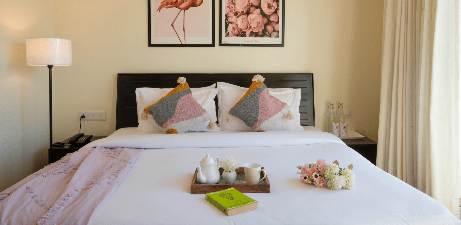 A bedroom at Perfectstayz Value Shimla (Namah Retreat) featuring a king size bed, wall art, side lamp, and a tray with a cup and kettle on the bed.