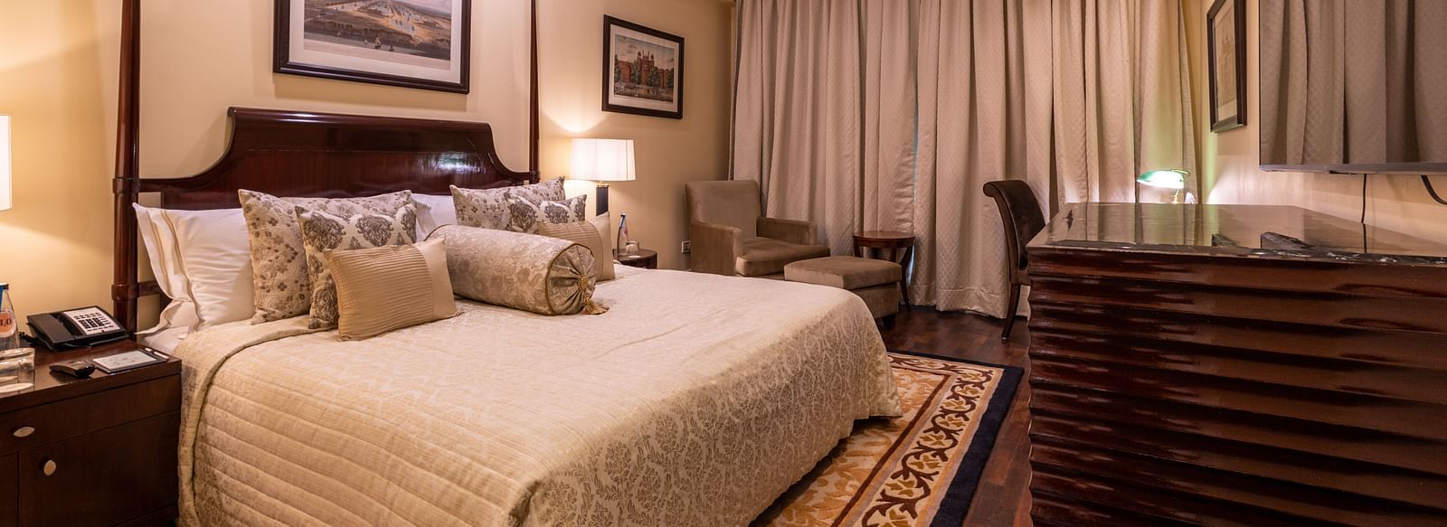 image of the bedroom of the heritage parlour room with a king size bed and beautiful photoframes hung on the wall - The Claridges New Delhi