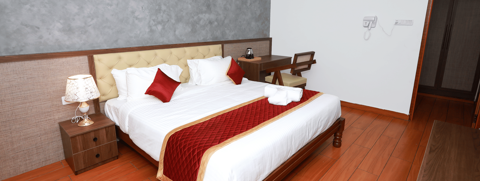 A double bed with a bed side table along with a lamp placed over it at the Standard Room at WOW Naturefull Resorts, Salem.