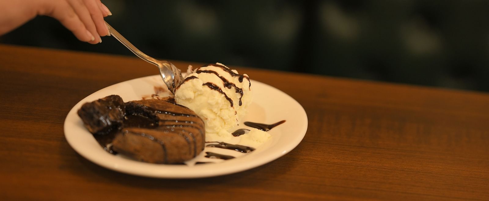 A delicious dessert, beautifully presented on a wooden table, awaits at Royal Comfort Regency.