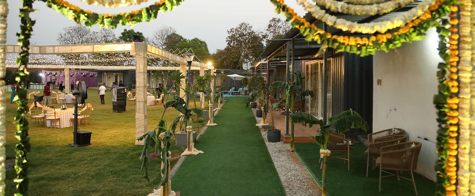 Venue entrance at Tisya Farms, Gurgaon with floral arch, green carpet, and guests walking inside.