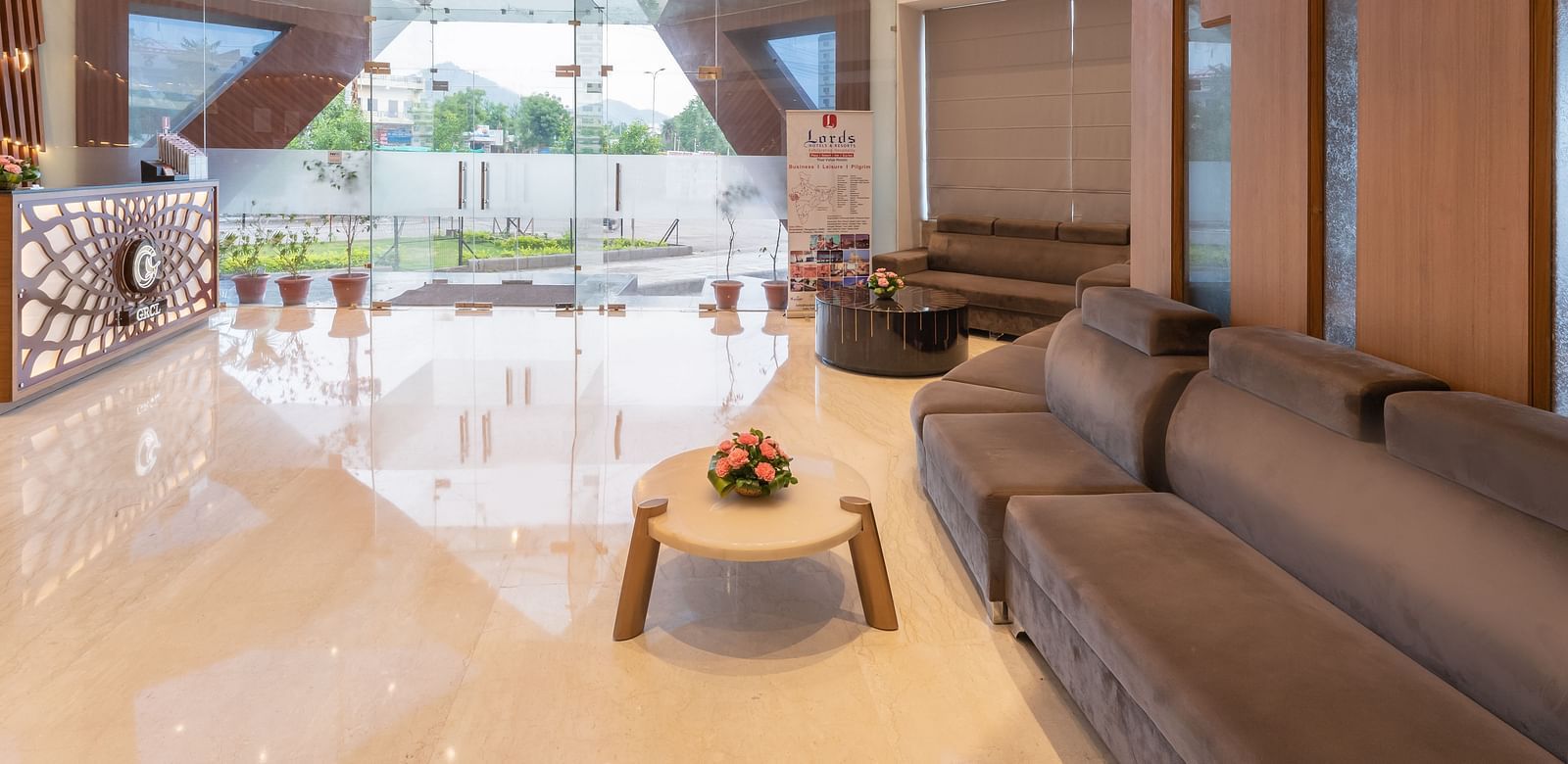 The spacious lobby of Lords Inn Udaipur showcases modern design with large windows, comfortable seating, and a polished floor.