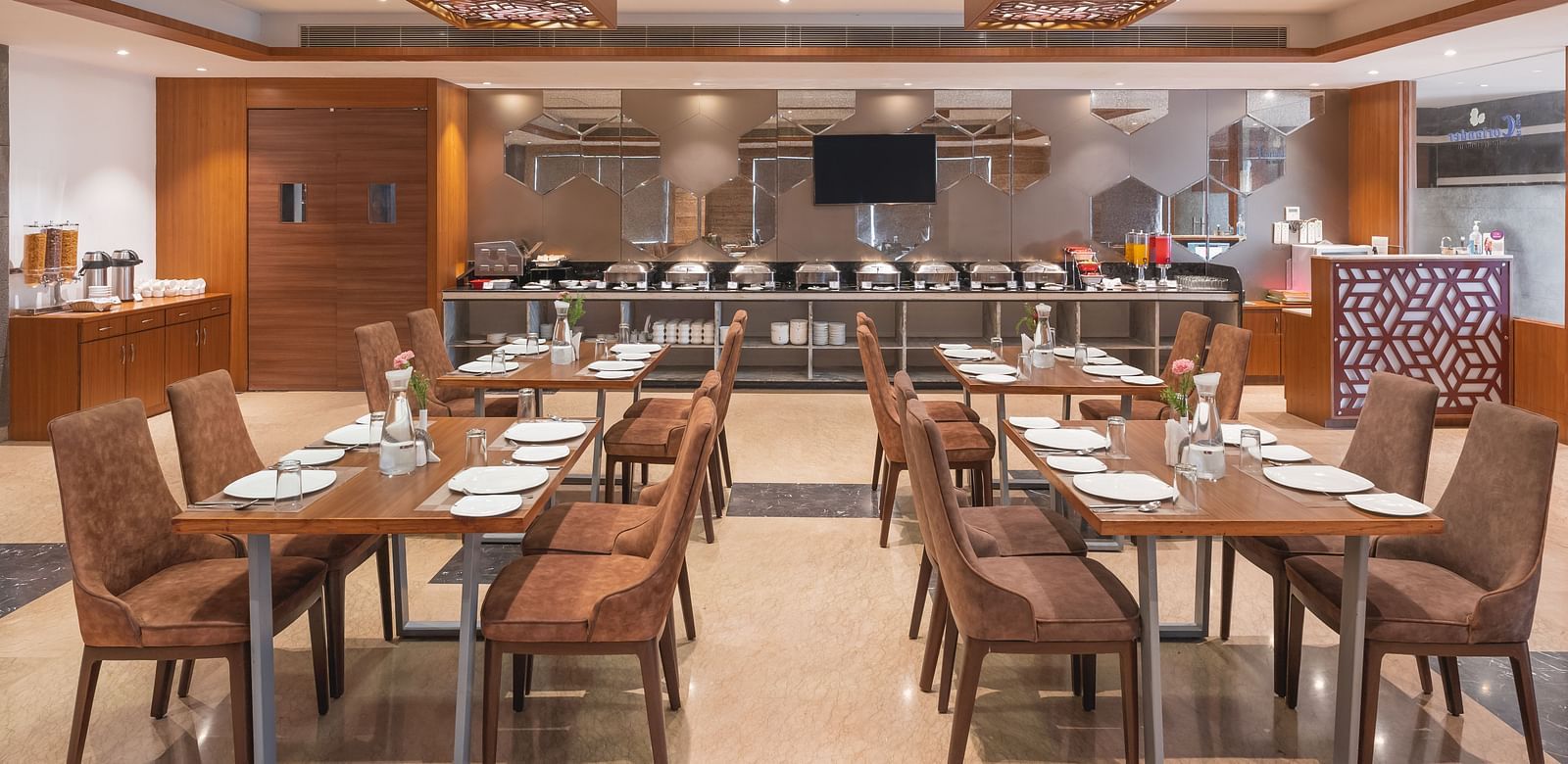The spacious restaurant at Lords Inn Udaipur is set with multiple tables and chairs, featuring a buffet area in the background.