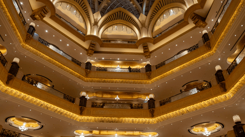 Symmetrical interior view of a multi-story building with ornate yellow arches, balconies, and dome structures.