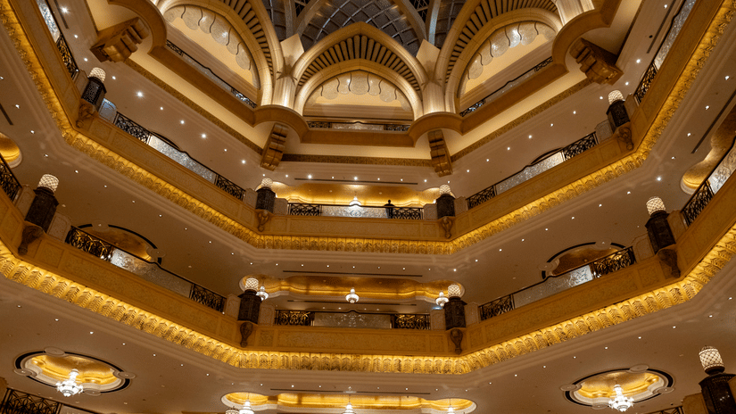 Symmetrical interior view of a multi-story building with ornate yellow arches, balconies, and dome structures.