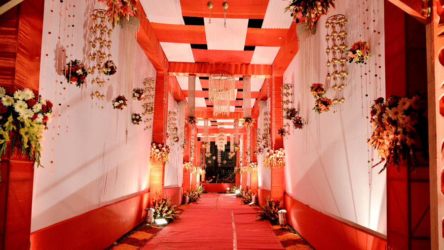 A red carpet walkway, lined with white and red draped pillars and floral hangings at Garh Govind.