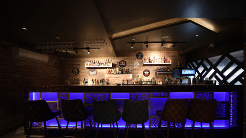 Bar counter that is decked with LED lights and shelves behind the table with liquor inside the bar - VITS Bharat Nanded