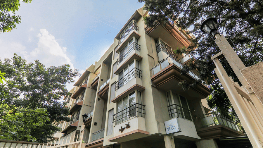 A hotel building with balconies and staircases, viewed from a low angle, with clear sky above.
