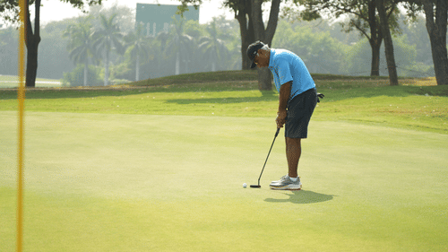Player concentrating while putting on the green during a golf tournament.