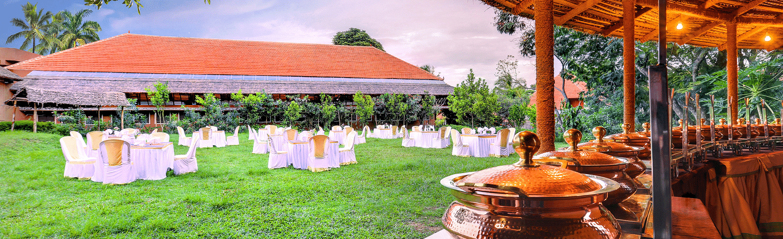 An overview of the lawn area as seen from the restaurant with elaborate seating arrangements at hoysala village resort.