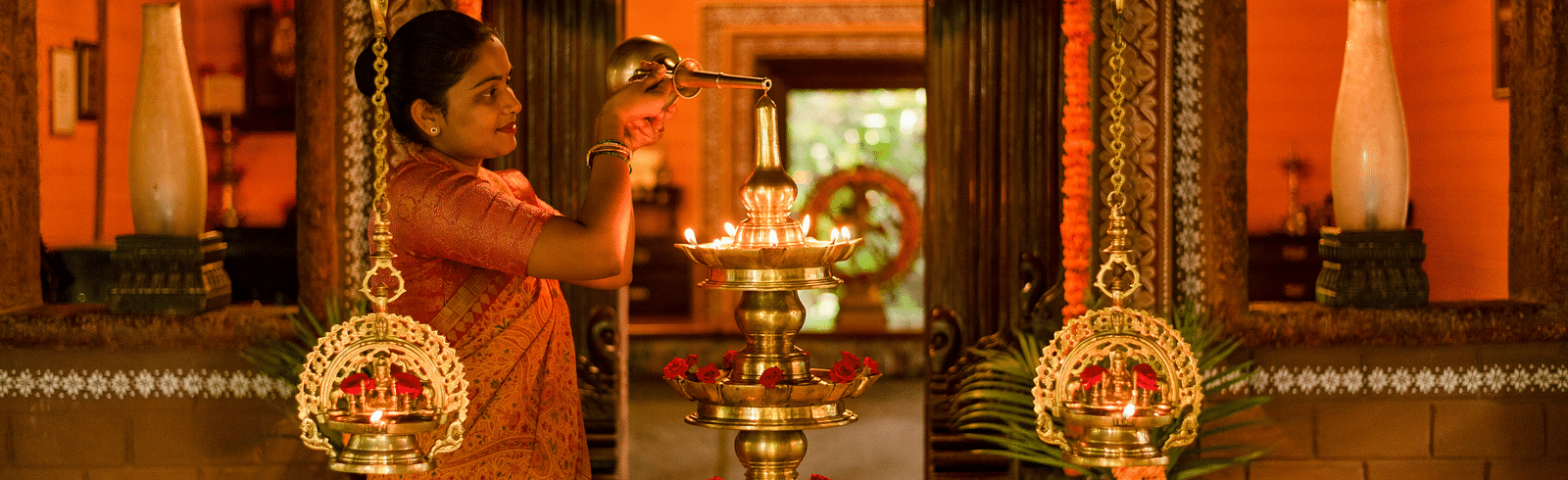 image of a staff pouring oil in the bronze lamp at Hoysala Village Resort, Hassan