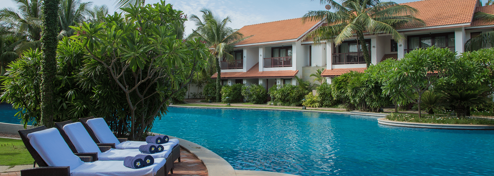 The meandering outdoor pool at a GRT hotel, framed by palms