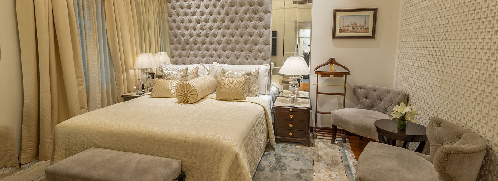 Superior Room at The Claridges New Delhi, featuring a cosy bed with bedside lights and two chairs arranged in the corner