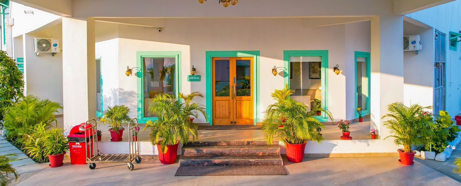 The entrance porch of Vedikant Resorts The Mallard Corbett with seating arrangements, potted plants, a chandelier, and visible main doors.