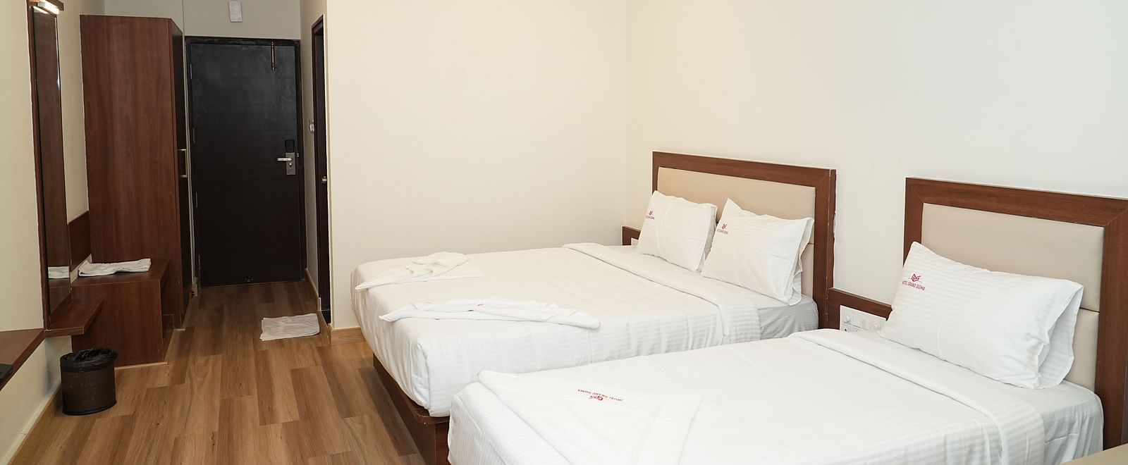 a room featuring a double bed along with a single bed with a wardrobe at the far end of the room - Hotel Grand Sigma
