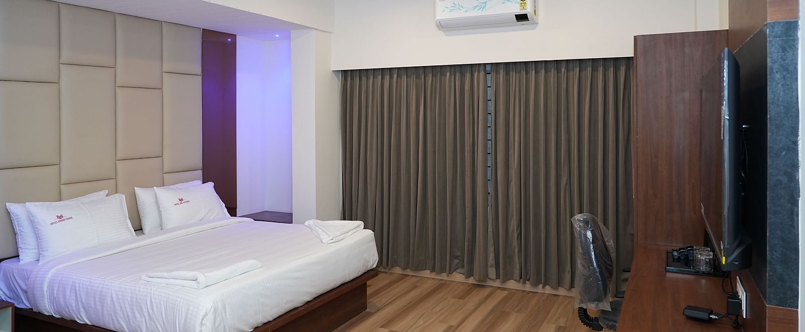 the suite room with a work desk and chair placed right opposite to the double bed - Hotel Grand Sigma