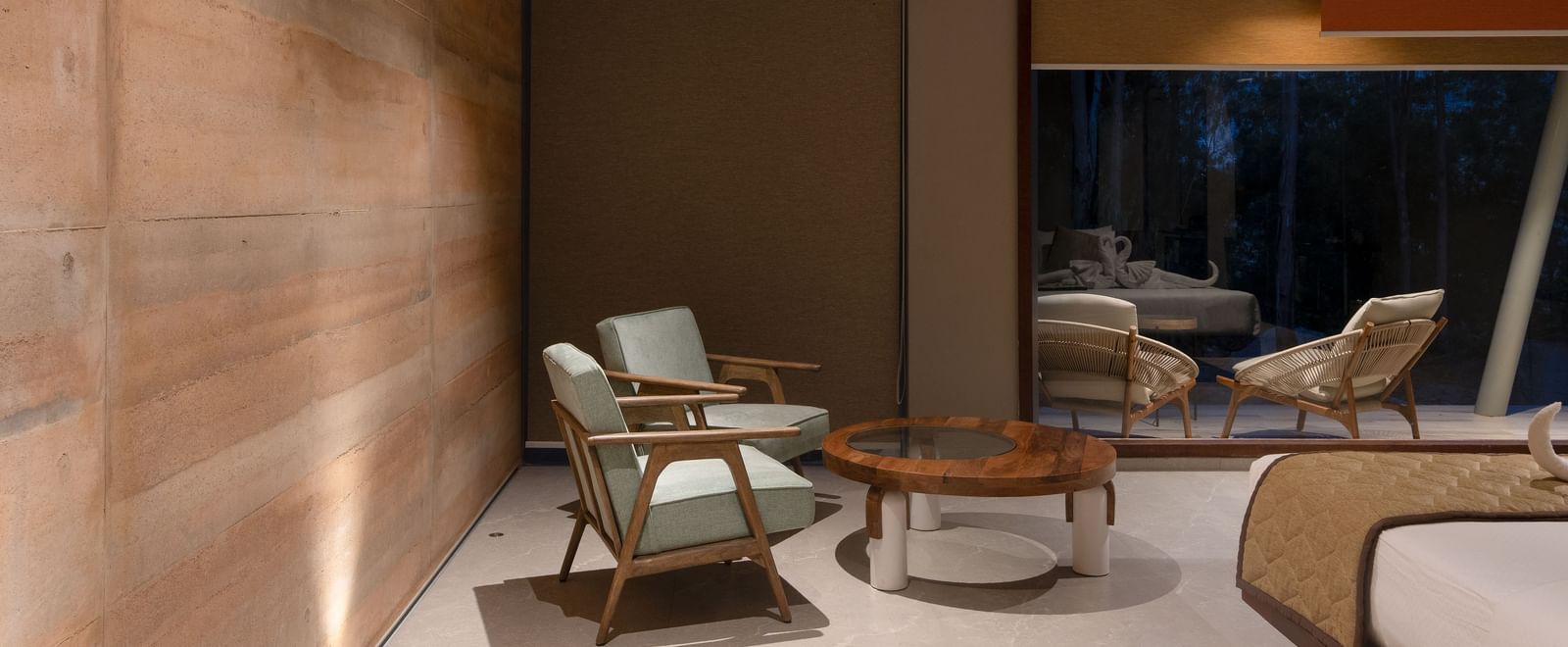 A modern hotel room with a bed, seating area, and a large window overlooking an outdoor space | Gaia Room | RD's Nature Retreat, Bangalore