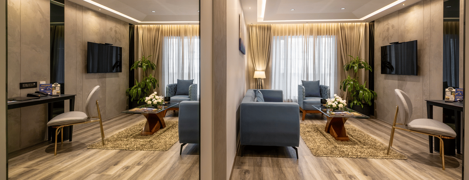 A spacious room in the Citrine Hotel with couches, a coffee table, a wall-mounted TV and a large mirror fixed on the wall.