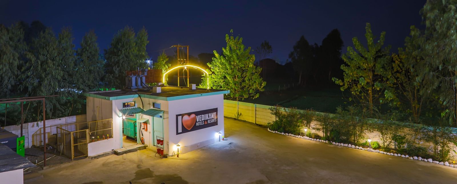 Night view of the resort's entrance gate, warmly lit with lush trees around at Vedikant Resorts The Mallard Corbett.