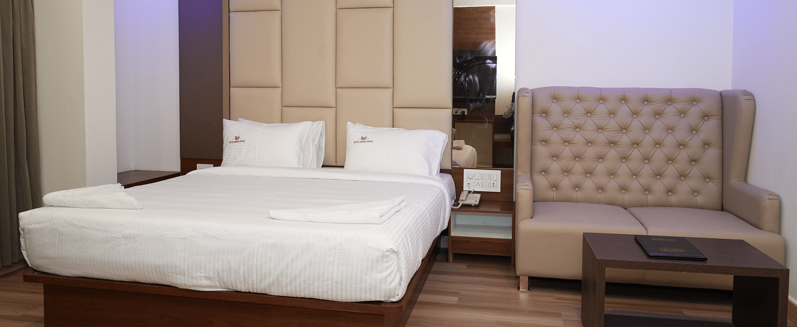 Suite featuring a plush double bed along with two full length mirrors wall mounted on either sides of the bed and a seating space next to it at Hotel Grand Sigma