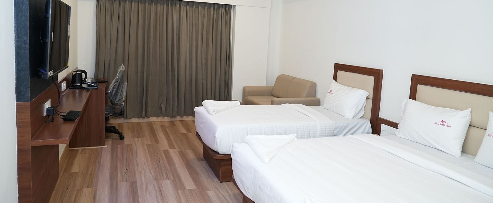 a room featuring a double bed along with a single bed along with huge windows with curtains drawn over it - Hotel Grand Sigma