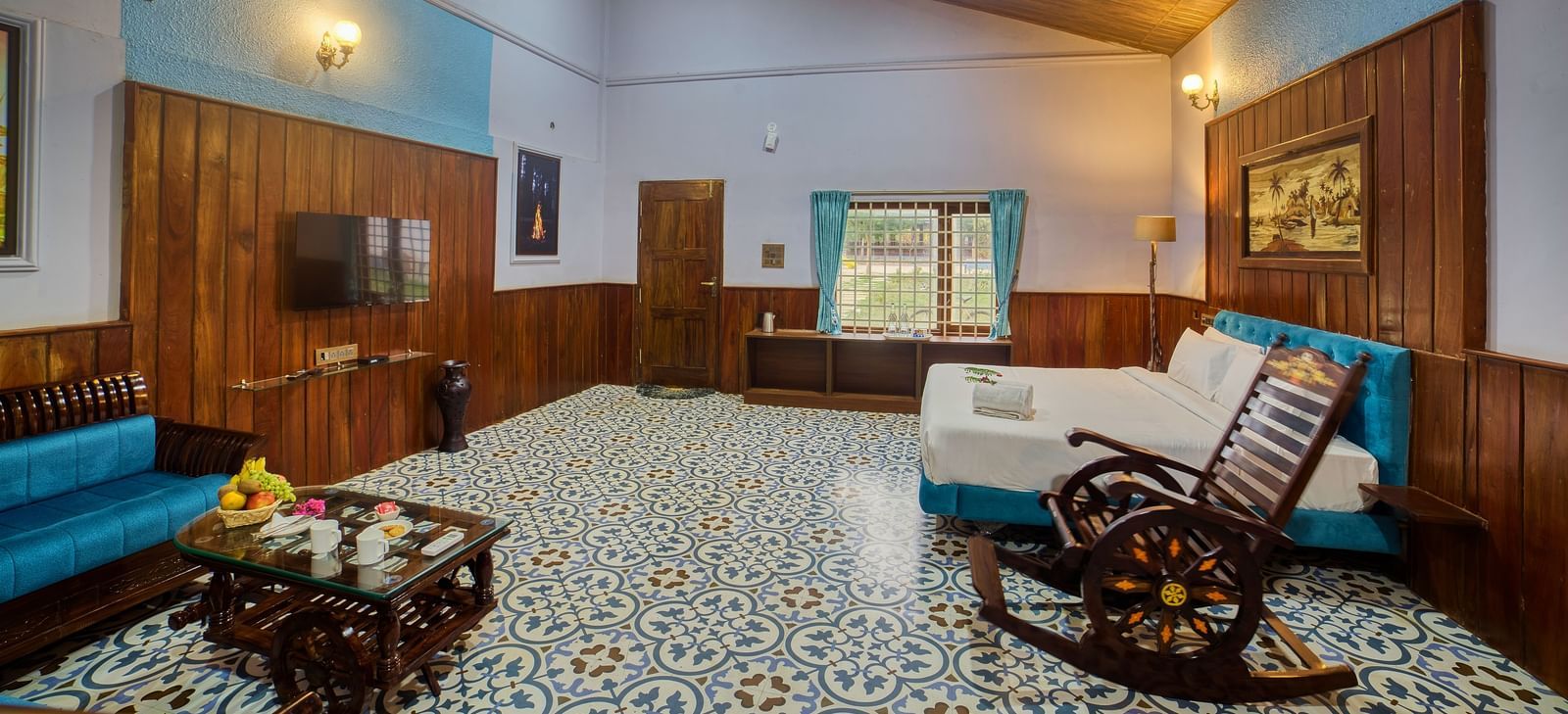 The interior of a room with a patterned floor, and wooden ceilings, featuring a sofa, a rocking chair, and a decorative coffee table. - Vintage Trails by Ilara