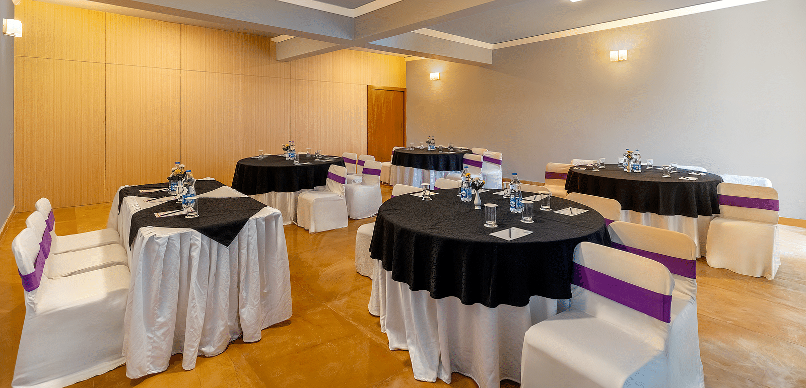 A room with round tables set with linens and chairs, prepared for an event - Via Lakhela Resort & Spa, Kumbhalgarh