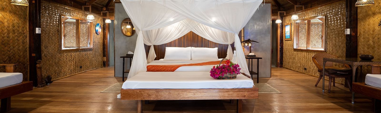 View of a wooden bedroom at Flower Island Resort with a white canopy bed and nightstands on both sides.