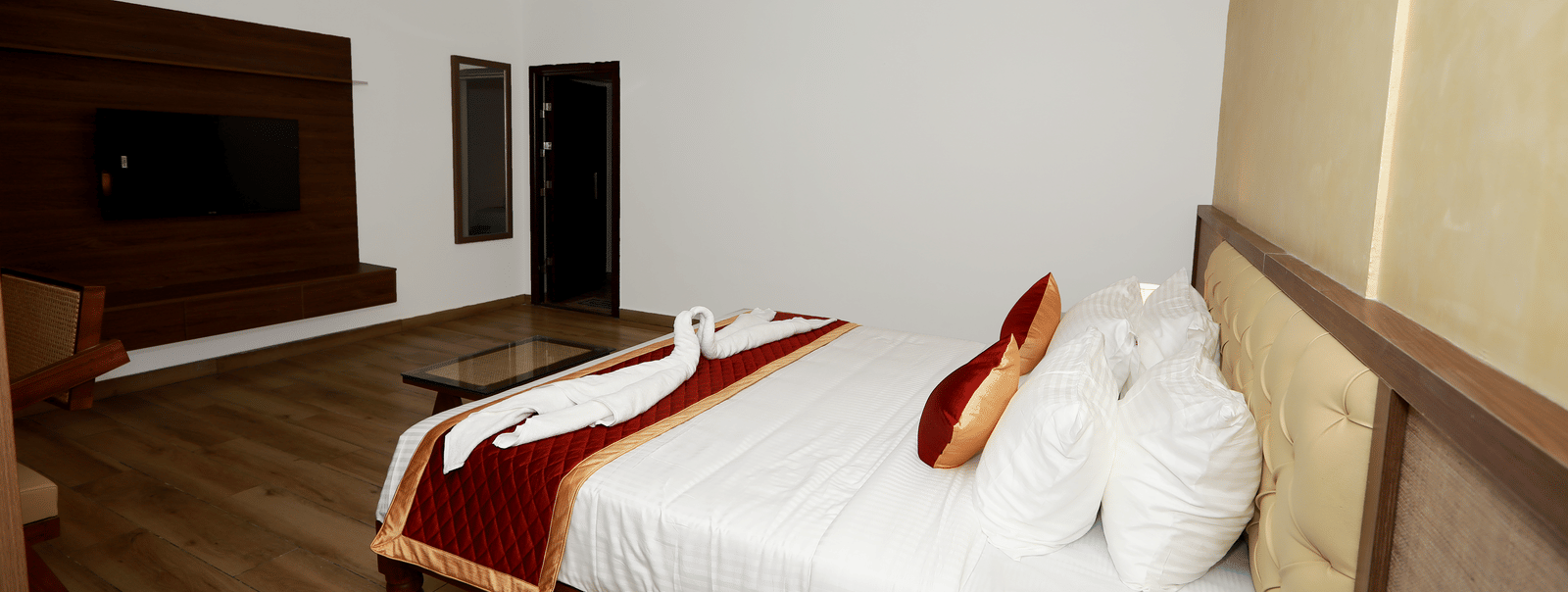Side view of the double bed at the Nature Luxury Room with towel swans kept on the bed runner at WOW Naturefull Resorts, Yercaud.