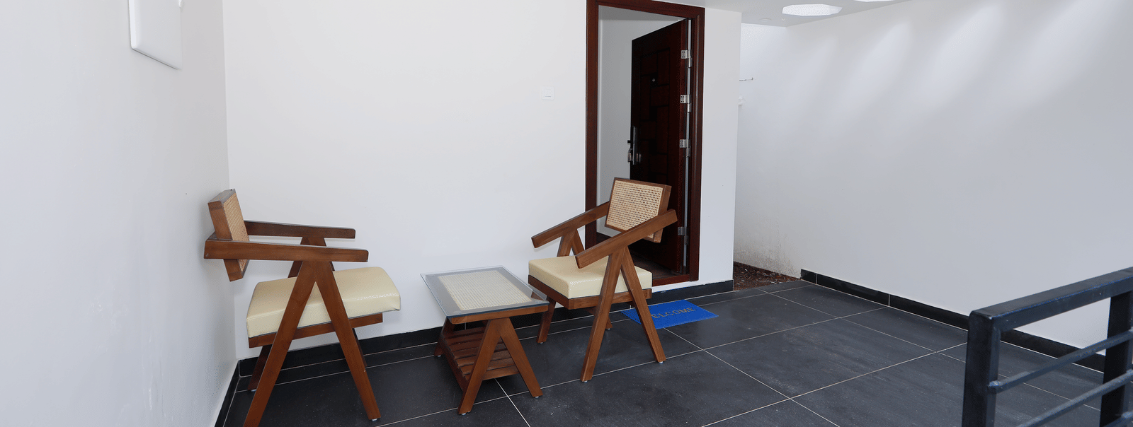 A sleek outside seating area with dark grey flooring, featuring 2 cushioned arm chairs in the Terrace Cottage at WOW Naturefull Resorts, Yercaud.