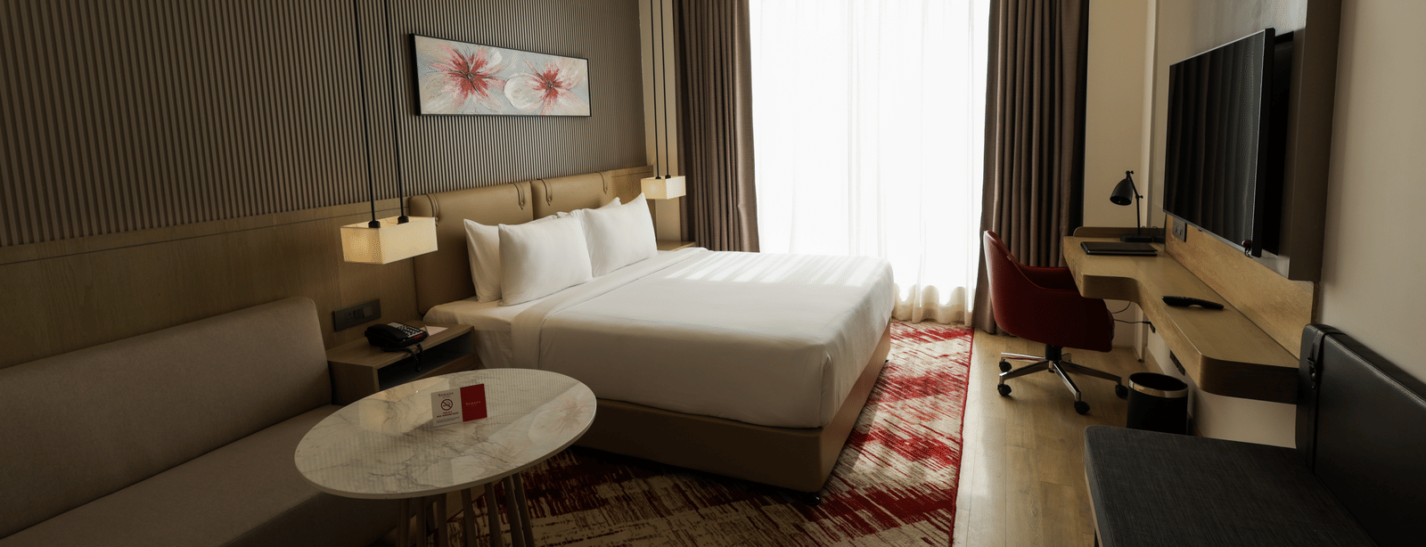 Room with seating area and a bed, offering ample natural light at Ramada by Wyndham Sonipat Murthal