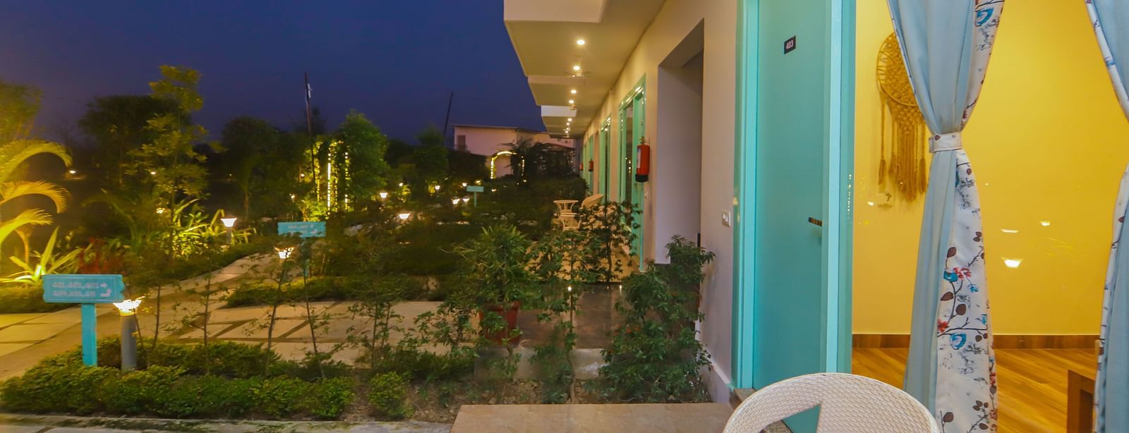 The exterior of rooms at Vedikant Resorts The Mallard Corbett at night shows balconies and illuminated pathways.