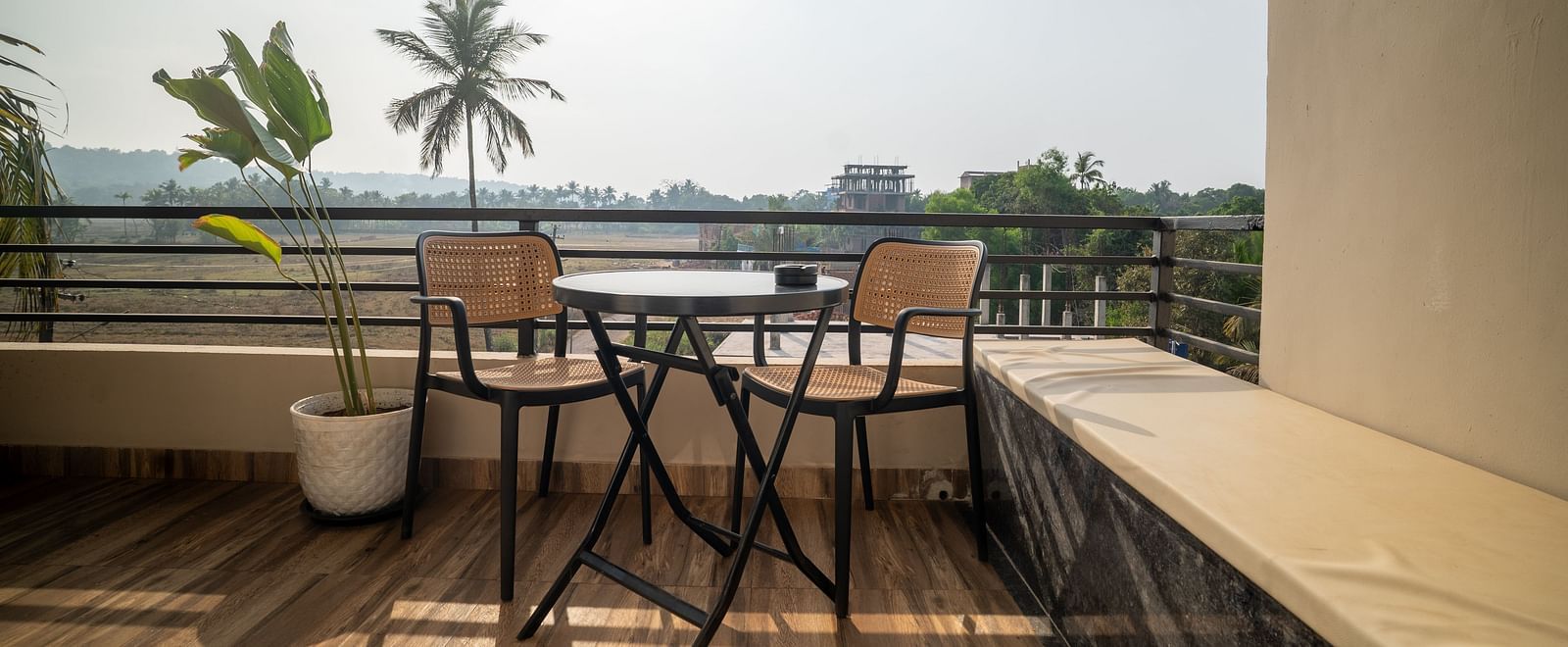A balcony with minimalist furniture overlooking lush greenery and palm trees at Kssemya.