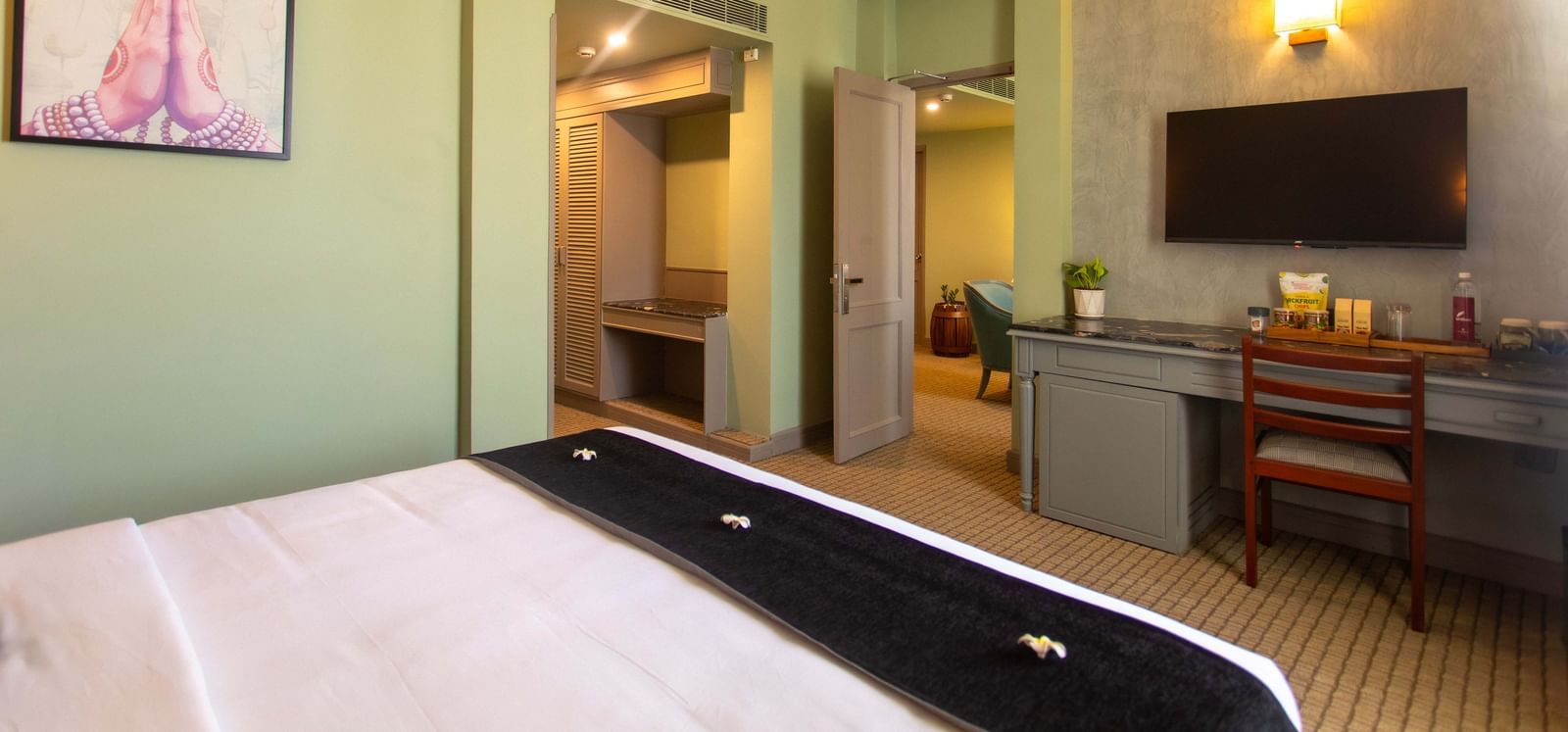  A hotel room at Shilton International, Kochi with a bed, television, and an open wardrobe area.