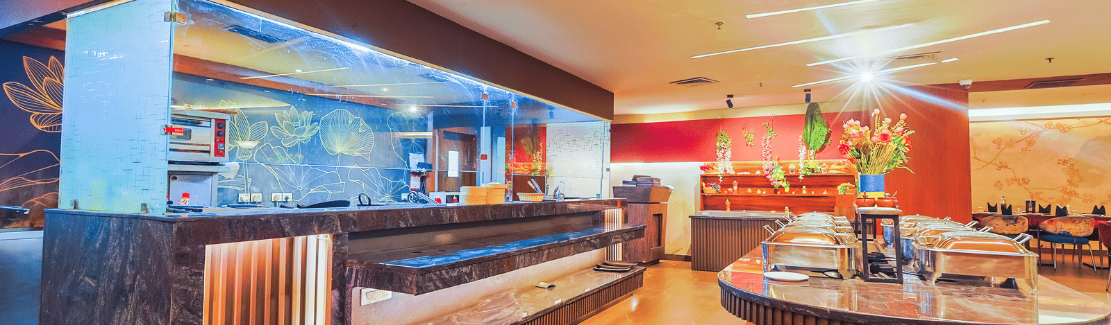 A well-lit and buffet area with a long serving counter,various food stations, and seating arrangements visible in the background.