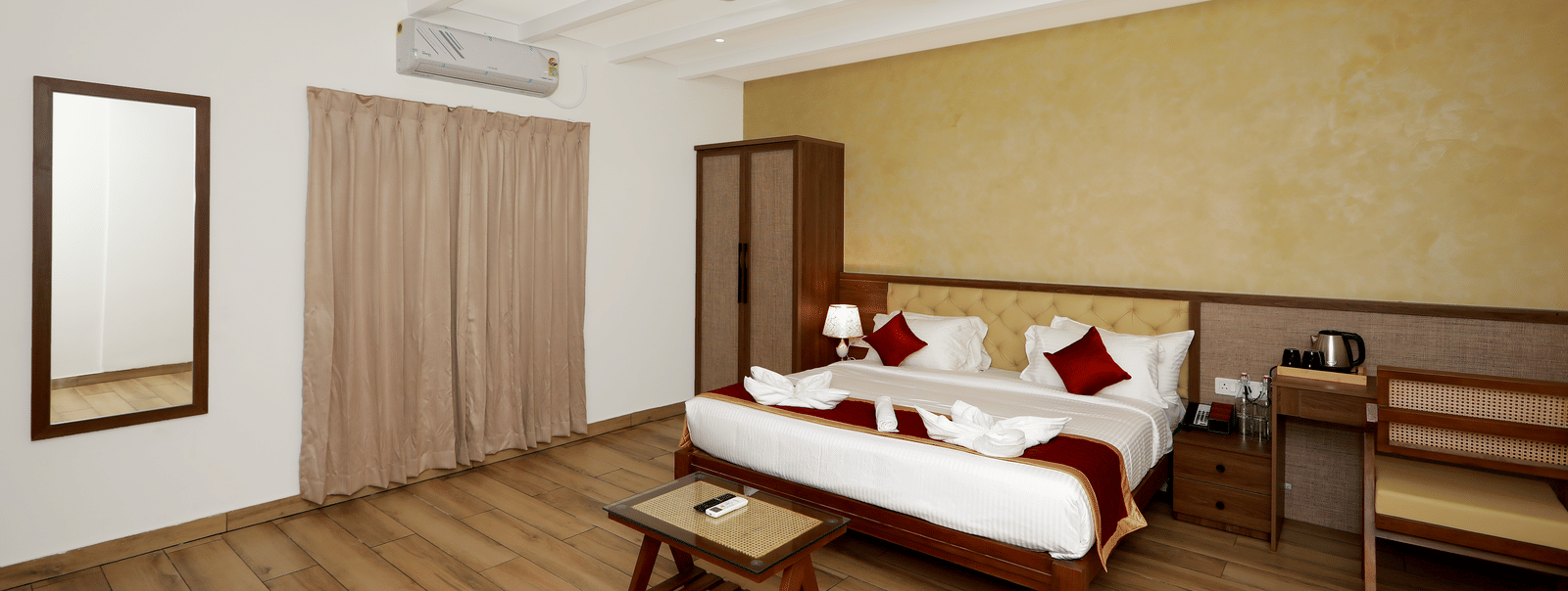 Full-view shot of the Terrace Cottage featuring a double bed, with a wall-mounted split AC above the window covered with beige-coloured curtains at WOW Naturefull Resorts, Yercaud.
