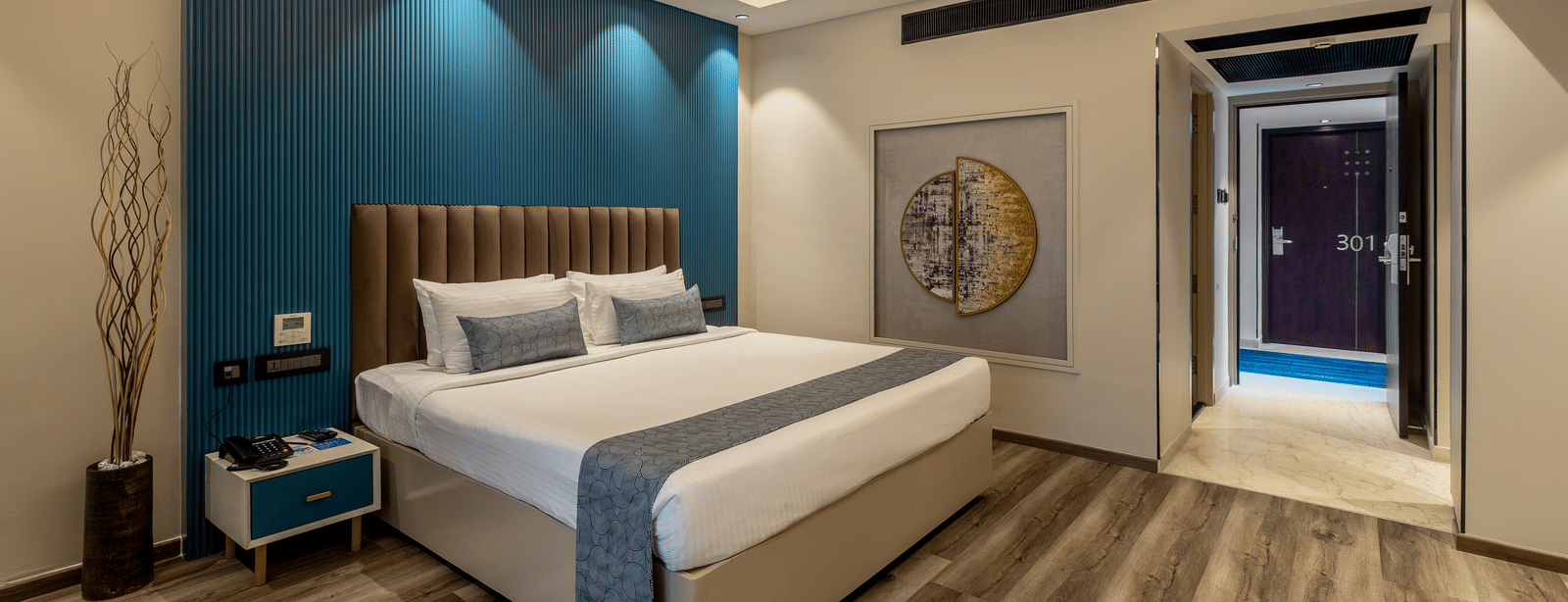A room at the Citrine Hotel with modern interiors, featuring a double bed and a blue accent wall.