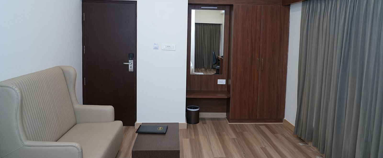 a seating area featuring a beige coloured couch with a coffee table placed in front of it - Hotel Grand Sigma