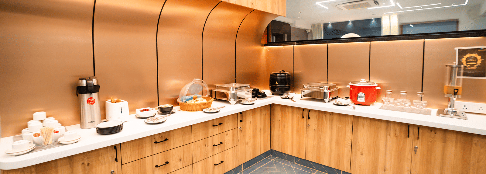 Dining area with buffet setup on an L-shaped counter featuring various dishes and cutlery at Sunrise Business Hotel, Hyderabad.